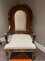 Front view of oak side chair showing upholstered seat and back, curved arms and turned legs.