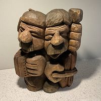 Front view of the wood carving showing two musicians closely positioned, one with accordion and one with lute-like instrument.