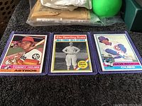 Three 1976 Topps baseball cards side by side in protective sleeves showing Tommy Helms, Lefty Grove, and Dave Rosello.