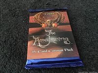 Front view of unopened 15-card caravan pack in metallic blue foil with The Awakening and Legend of the Burning Sand branding.