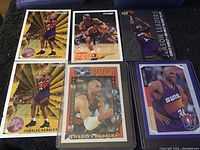Display of six Charles Barkley basketball cards in various designs and conditions on dark cloth background.