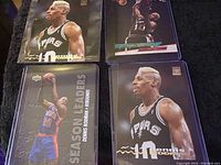 Top view of four Dennis Rodman basketball cards in protective sleeves, showing images of Rodman playing for Spurs and Pistons.