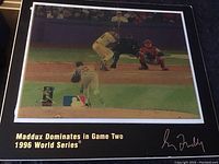 Framed color photo of Greg Maddux pitching in 1996 World Series with printed signature and text at bottom