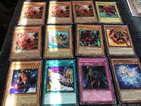 Photo showing 15 Konami Yu-Gi-Oh! trading cards spread out on a black surface with a variety of monster, spell, and trap cards.
