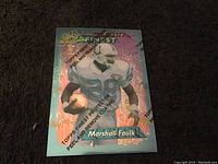 Front of the Marshall Faulk rookie football card with holographic finish and player in white Colts uniform, holding football.