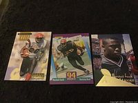 Five Marshall Faulk rookie football cards laid out on dark surface showing front faces clearly with different designs and images.