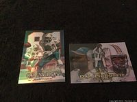 Front side of two O.J. McDuffie Miami Dolphins football collectible cards, one in action pose with holographic finish, the other featuring multiple images of the player.