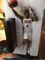 Joe Johnson basketball statue in white Team USA uniform number 4, shown in protective foam packaging with basketball in hand.
