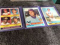 Topps 1976 baseball cards including a '76 Rookie Outfielders card and individual player cards for Roy Smalley and Mike Phillips laid out on a carpeted surface.