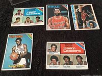 Image showing six vintage basketball cards, featuring players Norm Van Lier, Curtis Rowe, and team leader cards from Denver Nuggets and Boston Celtics.