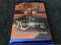 Front view of unopened 15-card caravan pack from Legend of the Burning Sands titled 'The Awakening'. Pack is sealed in blue foil.
