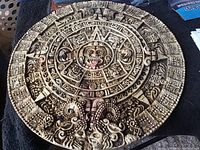 Top view of the circular stone carving depicting Mayan Aztec calendar symbols and central face motif.