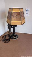 Full view of antique rotary phone converted to lamp showing cord and handset on side with decorative illustrated shade.