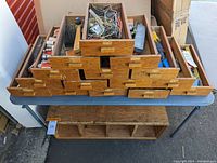 Overall view of stacked wooden drawers filled with tools and parts on a table outdoors