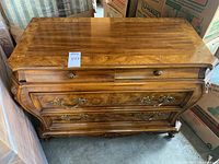 Full front view of the wooden dresser showing its curved French Provincial style, three drawers, and wood inlay top.