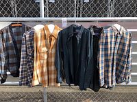 Front view of six hanging wool garments including one sweater and five shirts, showing various plaid patterns and colors