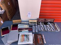 Full view of all pens and notebooks laid out on table including boxed pens and spiral notebooks.