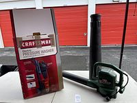 Photo showing Craftsman pressure washer box, pressure washer unit base, and blower/vacuum nozzle