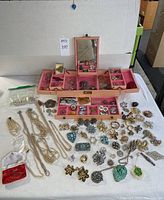 Overview of open pink wooden jewelry chest and items laid out
