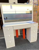 Front view of the white Boahaus desk showing six drawers and one center drawer with mirror resting behind it.