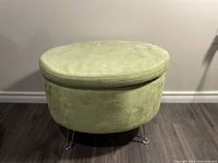 Front and side view of the small green plush storage ottoman showing its round shape and plush upholstery.