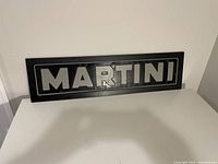 Front view of rectangular black and silver tin wall art sign spelling 'MARTINI'.