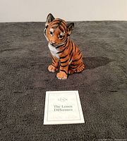Front view of the tiger cub porcelain sculpture with a Lenox information card in front
