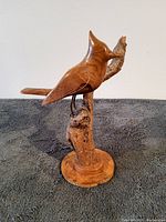 Front right angle view of wooden cardinal sculpture showing smooth carving details and wood base