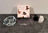 Photo of all items together including the glass candle holder, the black and white cat salt and pepper shakers, the pewter pin and the decorative box with dog and cat pictures