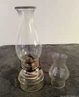 Front view of the antique Reids Perfect oil lamp with the taller glass chimney attached and smaller chimney beside it on the right.