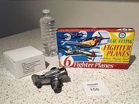 Photo showing the boxed foam fighter planes, metallic airplane perpetual calendar, and a water bottle for scale on a speckled countertop.
