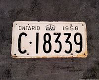 Front view of the vintage 1958 Ontario vehicle license plate showing black embossed characters on a white background with some rust and paint wear.