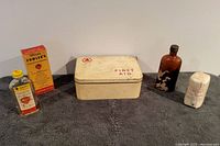 Photo showing full assortment of vintage 1960s medical supplies including a Cuxson Gerrard First Aid tin, Doctor Fowlers bottle with original box, brown glass Dr. Lambert bottle, and a crepe bandage.