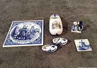 Photo showing all six inclusions: square tile with milkmaid, clog-shaped box, two miniature decorative clogs, small windmill tile, Delft couple figurine