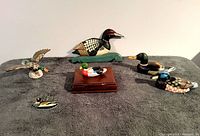 Photo showing all vintage duck lot items spread on a cloth, including wooden carvings, card holder with cards, mechanical duck and wall hook