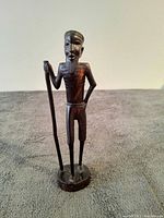 Front view of the vintage ebony wood African man sculpture showing detailed facial features and staff.