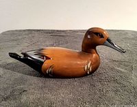 Side view of the wooden duck carving showing detailed painted wings and tail with a smooth brown finish.