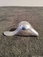 Side view of a small aluminum alloy beaver sculpture showing its smooth, shiny surface and flat tail