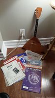 Photo of balalaika and assortment of sheet music placed on floor against wall