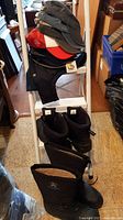 Full lot arrangement showing boots and stacked hats on a white ladder in an indoor setting.