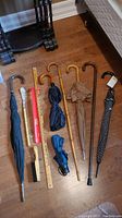All items laid out together on the floor showing full set of umbrellas, canes, yardstick, brush, and shoe horns.