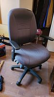 Front view of dark gray fabric office chair with armrests, cushioned seat and back, and caster wheel base.