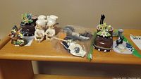 Overview of lot displayed on wooden shelf with napkin holders, bird figurine, and assorted fridge magnets.