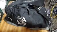 Black hockey bag with white logo, lying closed on the floor.