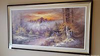 Full view of the framed oil painting showing cabin by stream with mountains and autumn foliage.