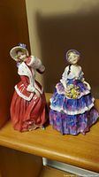 Front view showing both figurines: Christmas Morn in red cloak and Irene in purple dress