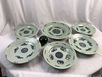 Overview of one large serving plate centered among five smaller plates with green apple size reference