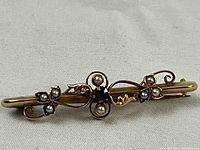 Top-down view of brooch showing front design, ruby and seed pearl settings