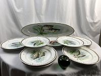 Oval serving platter and multiple dinner plates arranged with green apple for scale