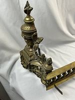 Left-side urn finial atop acanthus leaf scrolling with portion of baluster rail and base visible